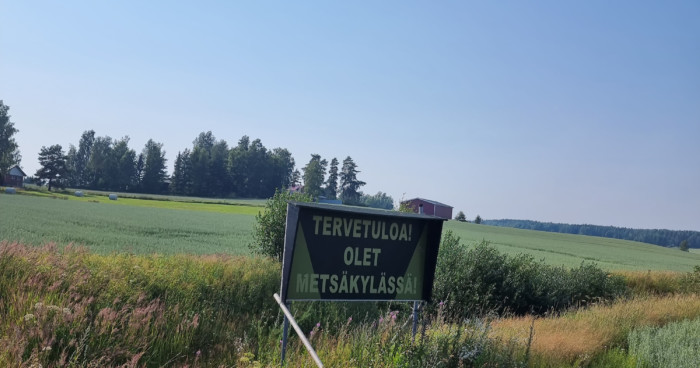 Kyltti Tervetuloa, olet Metsäkylässä peltomaisemassa.