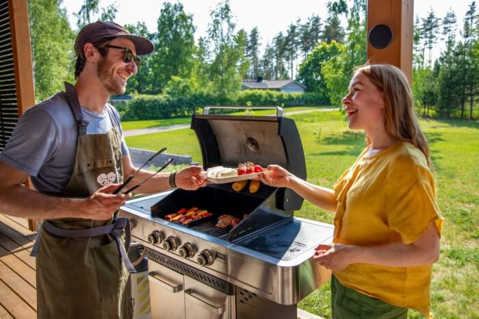 Pariskunta grillaamassa kaasugrillillä omakotitalon terassilla.