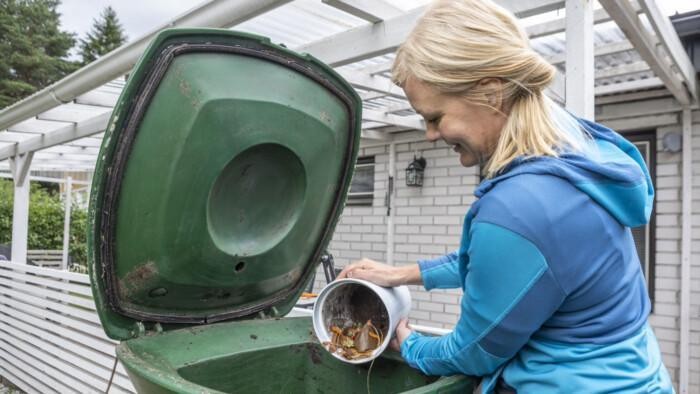 Nainen kaataa ämpäristä biojätettä kompostoriin.