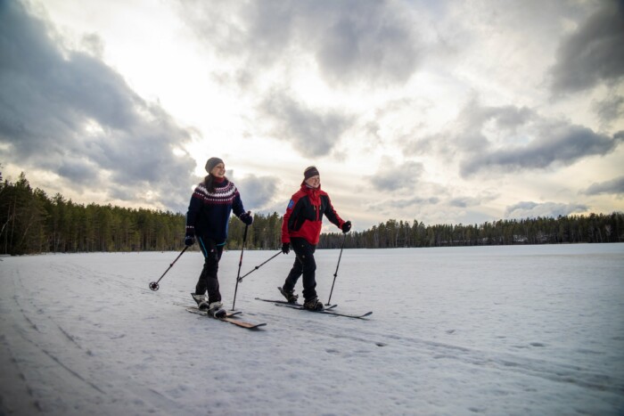 Kaksi naista hiihtää järven jäällä.